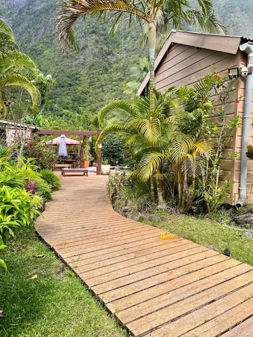 Allée en bois du jardin tropical de la chambre d'hôtes, vers la terrasse